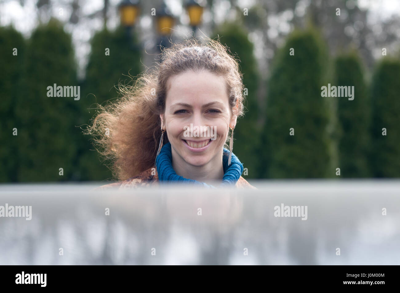 Wunderschöne lächelnde Frau mit fliegenden Haare vor Zypressen Wand Stockfoto