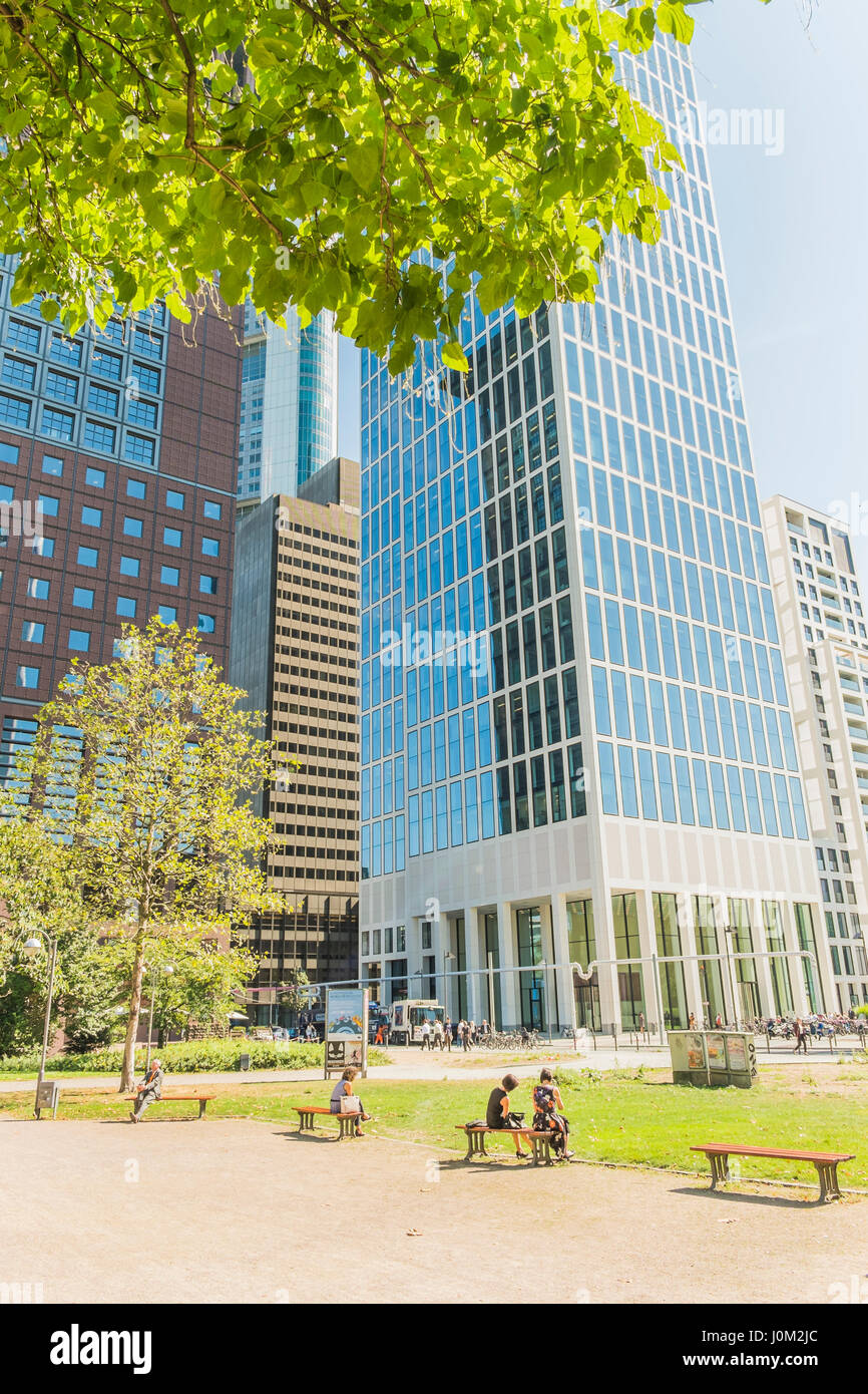 Mitarbeiter, die ein Mittagessen brechen im öffentlichen Park Taunusanlage mit Bürogebäude im Hintergrund Stockfoto