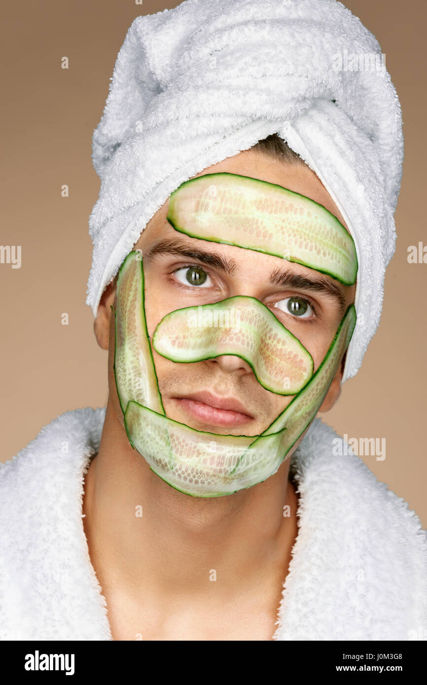 Modische Mann empfangen Gesichtsmaske Gurke. Das Gesicht des Mannes kosmetischen Verfahren. Pflege selbst Stockfoto