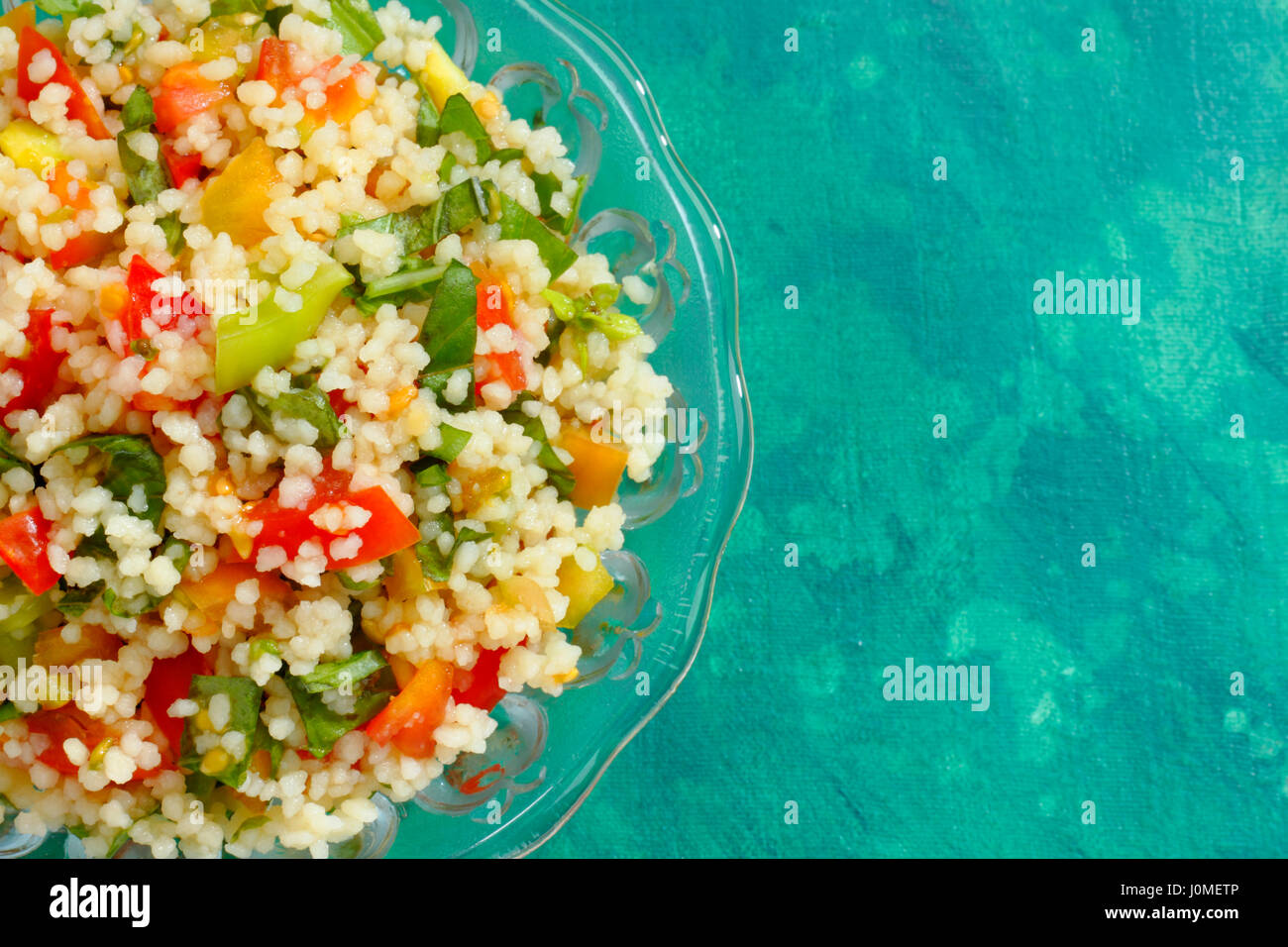 Glasschale mit Taboulé (Arabischer Salat) über gemalte grüne Textil Hintergrund. Draufsicht mit Textfreiraum. Stockfoto