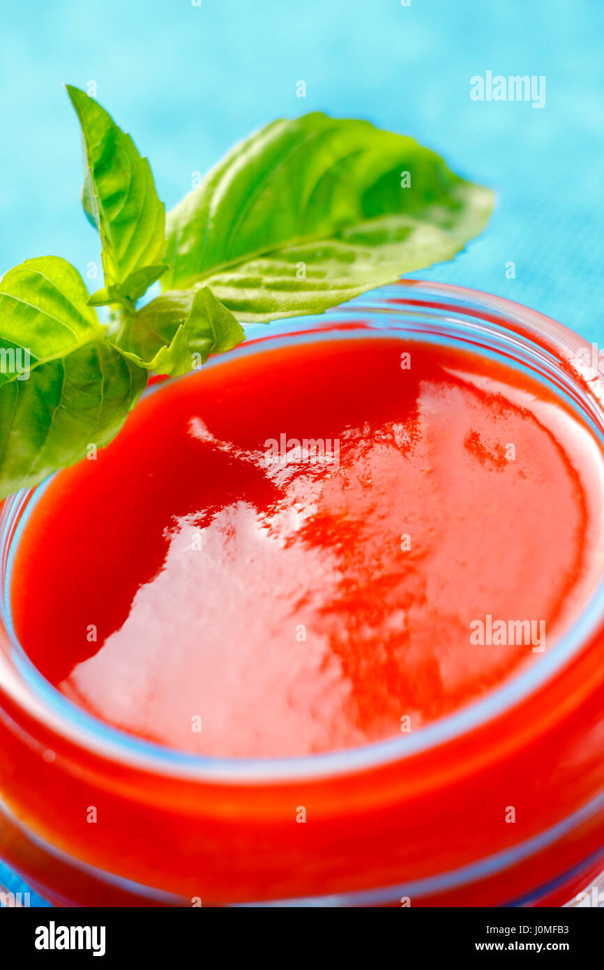 Tomatensauce in Glasschale mit Basilikum Blätter Stockfoto