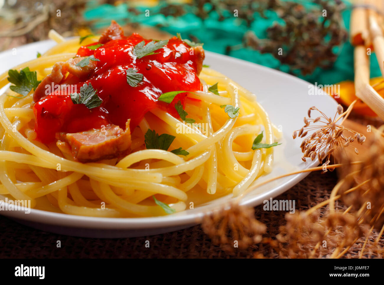 Spaghetti mit Tomatensauce, gebratenem Speck und gehackte Petersilie auf Teller mit unscharfen Hintergrund Stockfoto