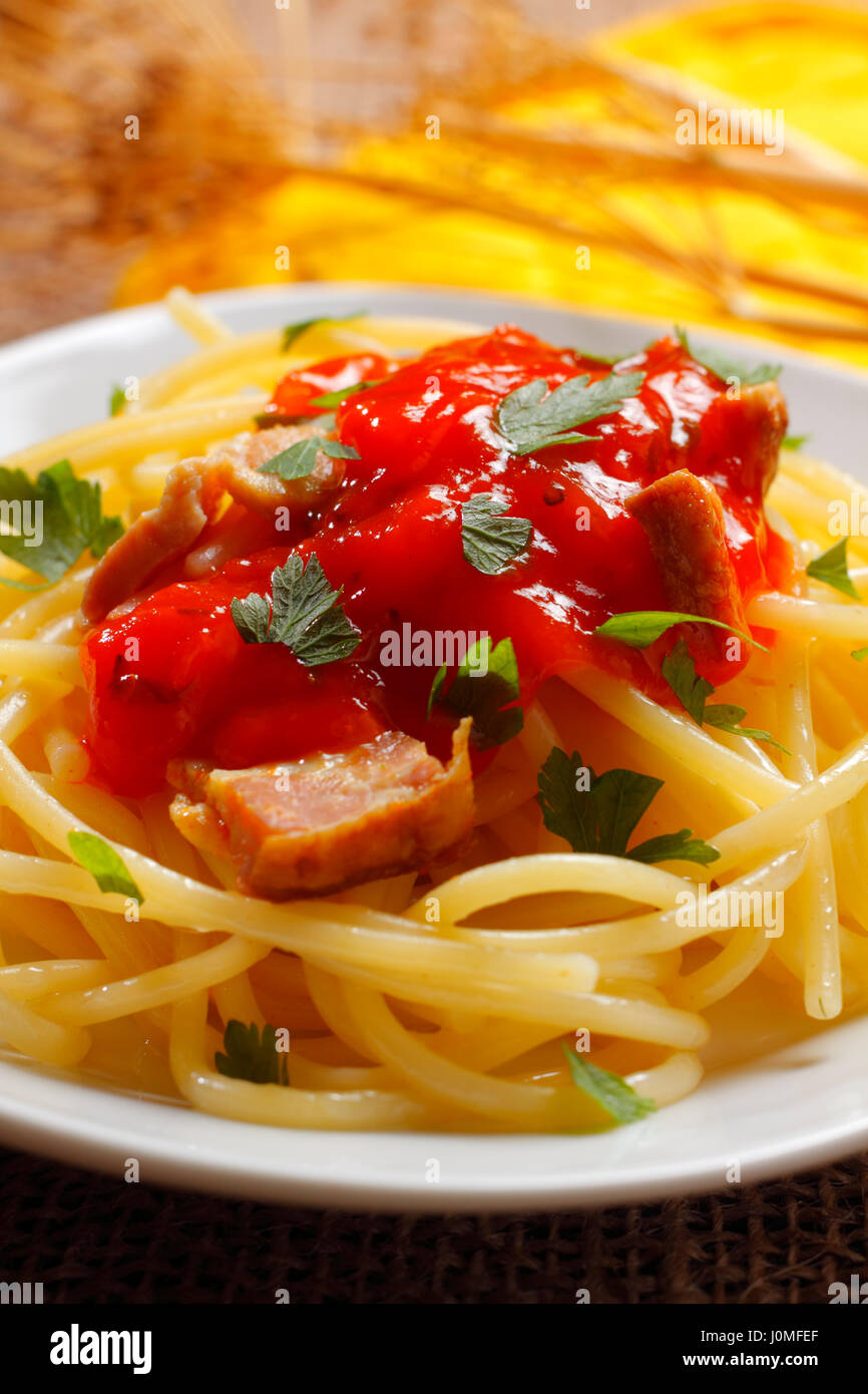 Spaghetti mit Tomatensauce, gebratenem Speck und gehackte Petersilie auf Teller mit unscharfen Hintergrund Stockfoto