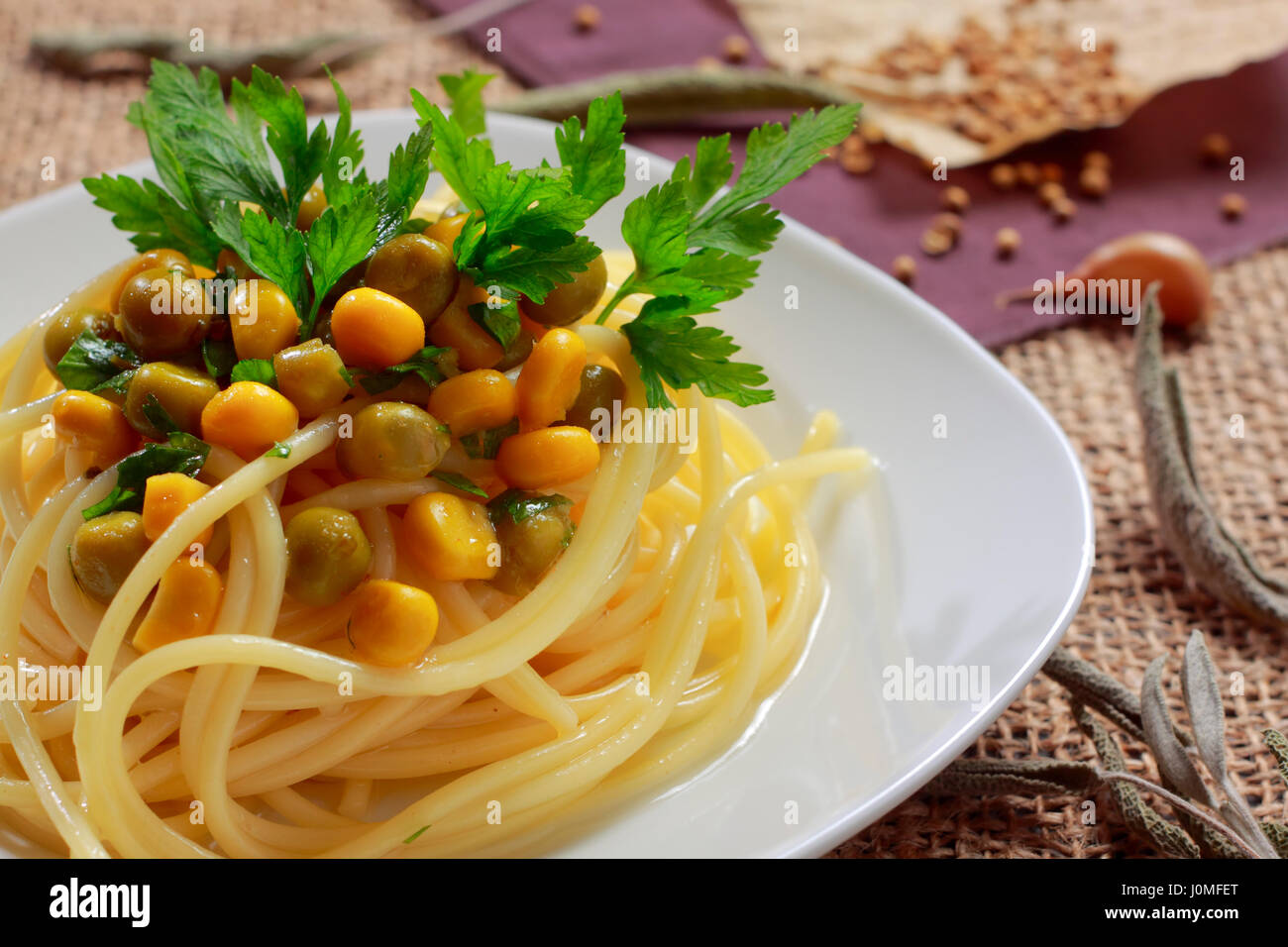 Spaghetti mit grünen Erbsen (konserviert), Zuckermais und Petersilie Blätter auf Platte Stockfoto