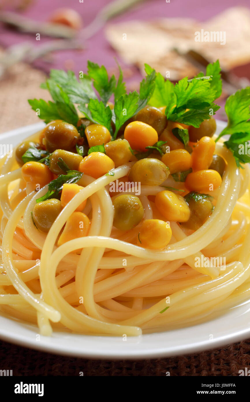 Spaghetti mit grünen Erbsen (konserviert), Zuckermais und Petersilie Blätter auf Platte Stockfoto