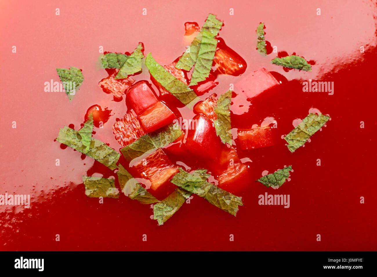 Nahaufnahme von Sahne Tomatensuppe mit gehackten Paprika und grünen Kräutern Stockfoto