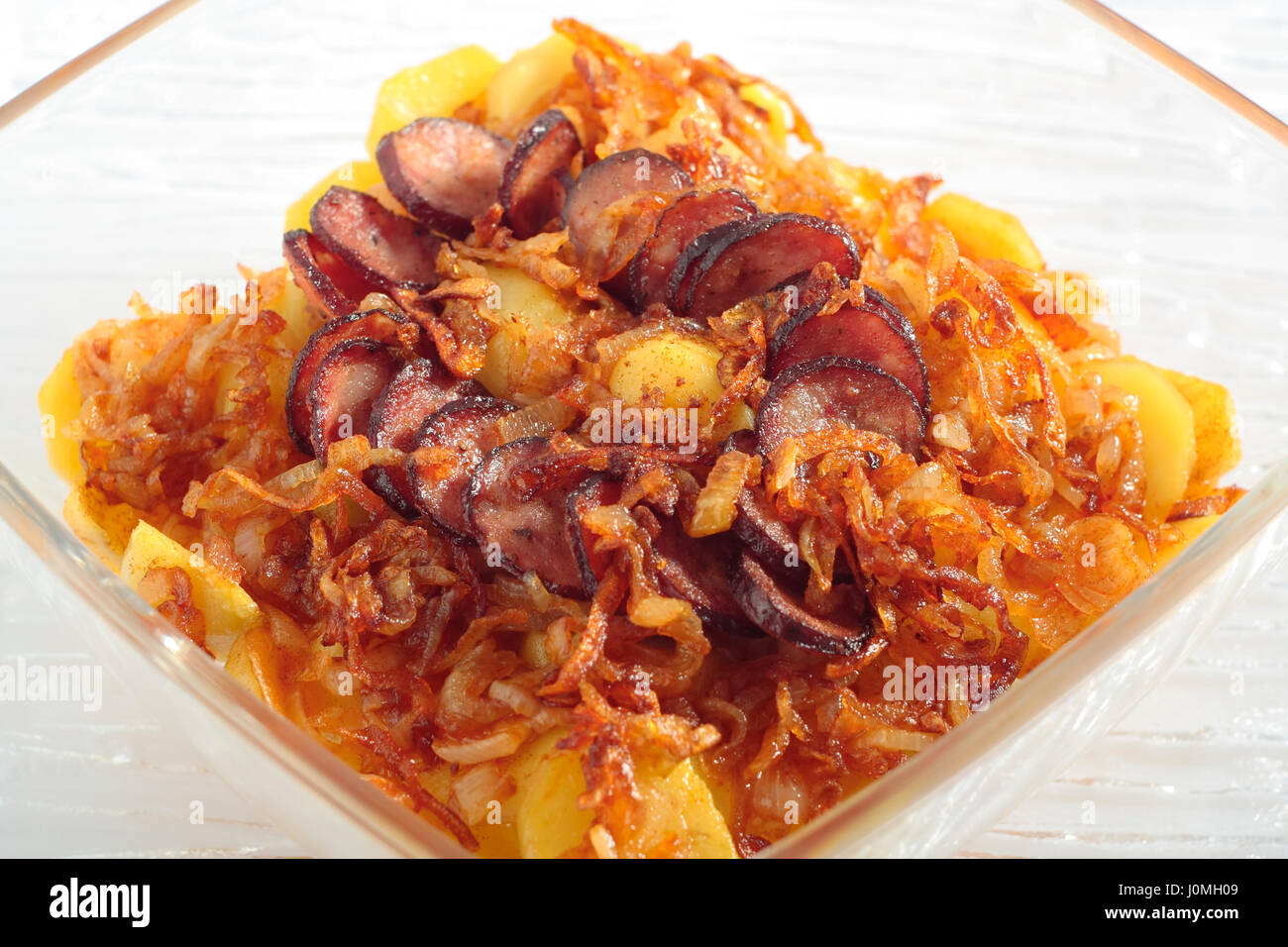 Gebratene Zwiebeln, die Kartoffeln Scheiben und die Scheiben Wurst, geröstet in hitzebeständigen Glasgefäß. Ansicht von oben. Stockfoto