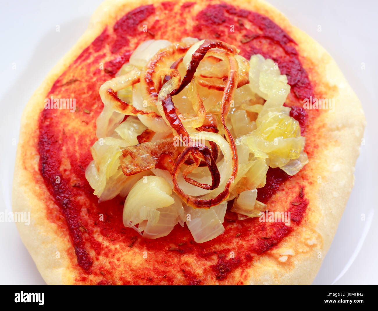 Kleine Pizza (Pizzette) mit gebratenen Zwiebeln und Tomaten Sauce auf einem Stapel von weißen Platten von oben Stockfoto