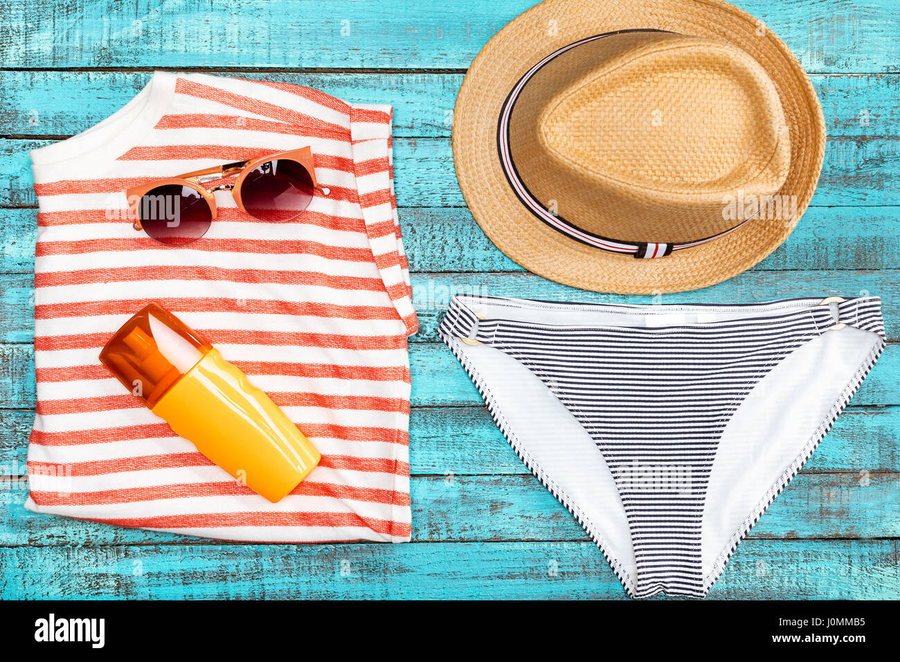 Draufsicht der Strohhut, Bikinihöschen, Sonnenbrille und Sonnencreme auf Holztisch, Sommer-Konzept Stockfoto