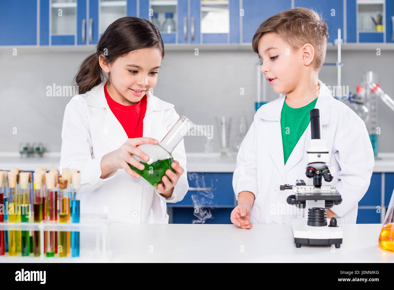 Zwei Kinder in weißen Kitteln machen chemischen experimentieren im Labor Stockfoto