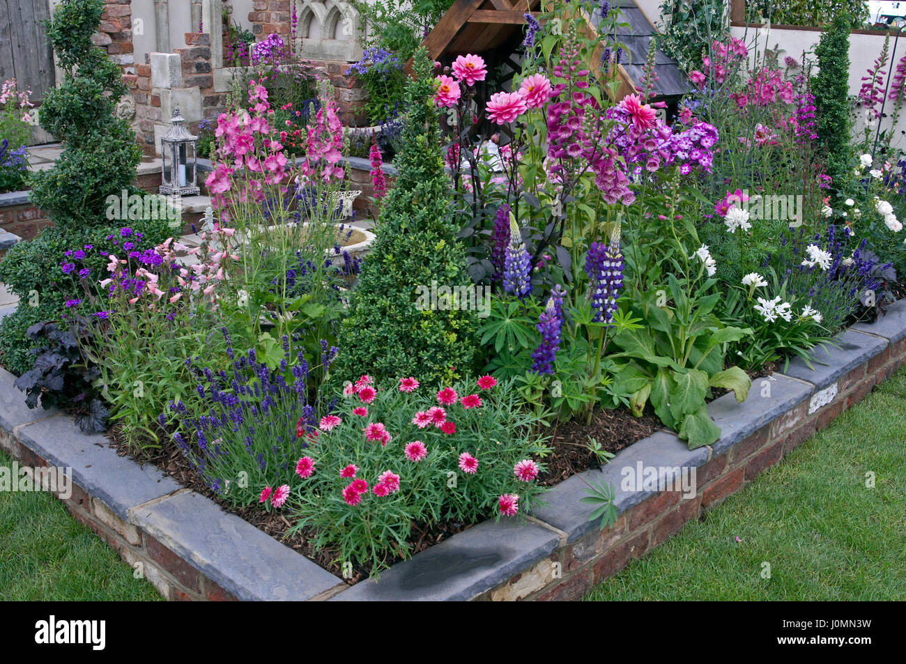 Bunte Pflanzen in einer erhöhten Blumenbett ein Patio-Garten Stockfoto