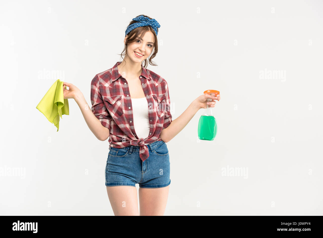 Attraktive junge Frau mit Sprühflasche und Lappen in die Kamera Lächeln Stockfoto