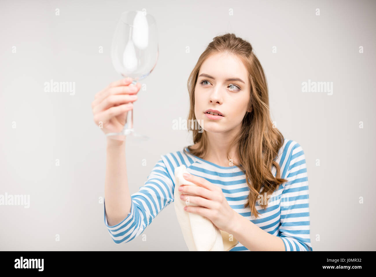 Junge attraktive Frau holding Lappen und mit Blick auf saubere Weinglas Stockfoto
