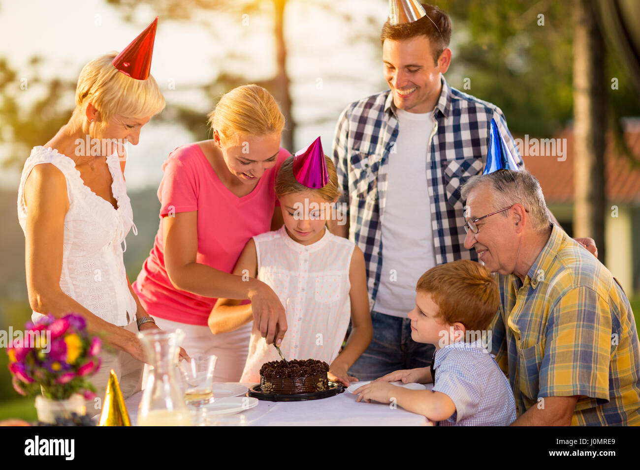 Lächelnde Mutter schneiden Geburtstagstorte Stockfoto