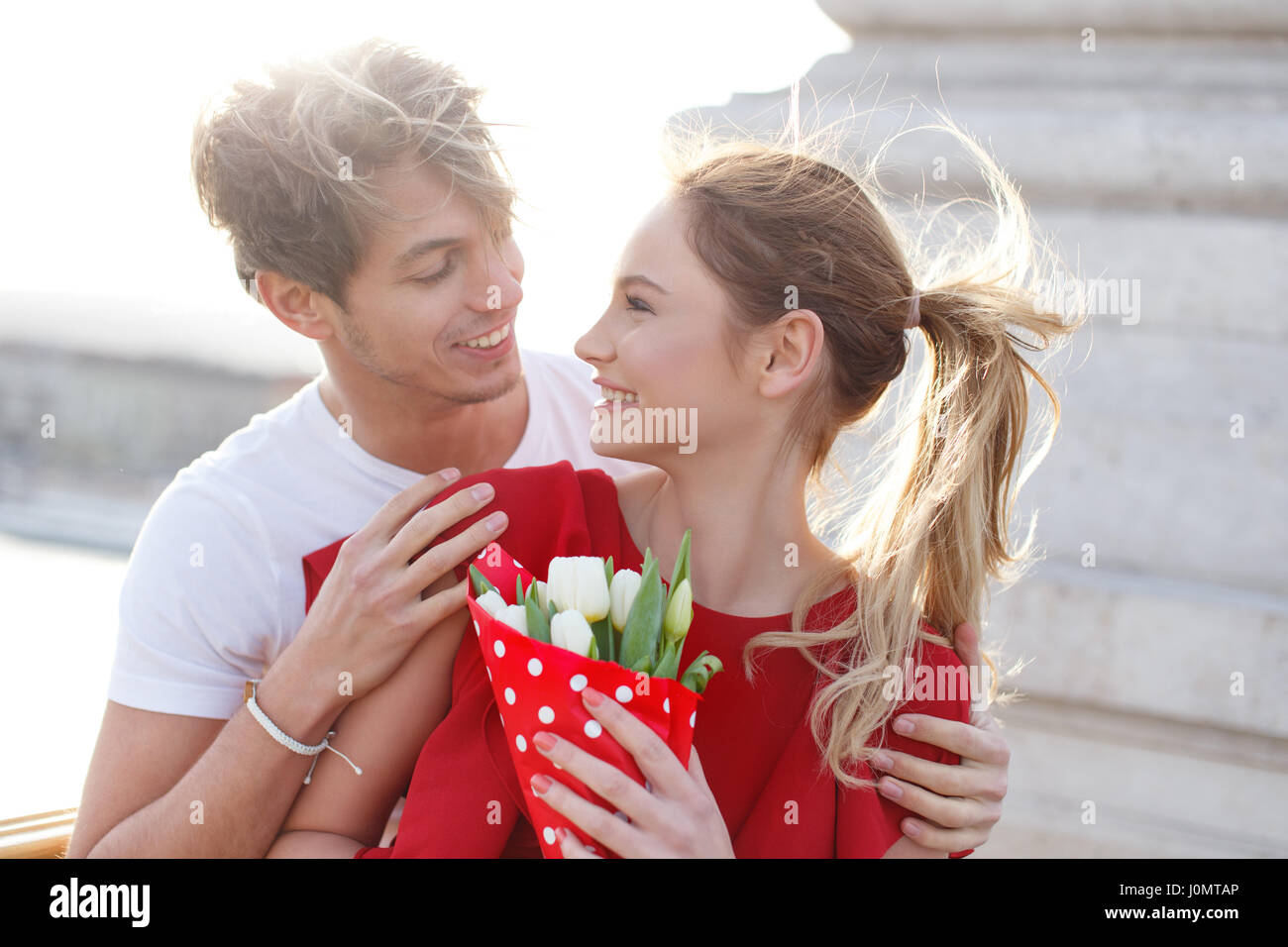 Glückliches junges Paar dating outdoor, Frau im roten Kleid und bouquet Stockfoto