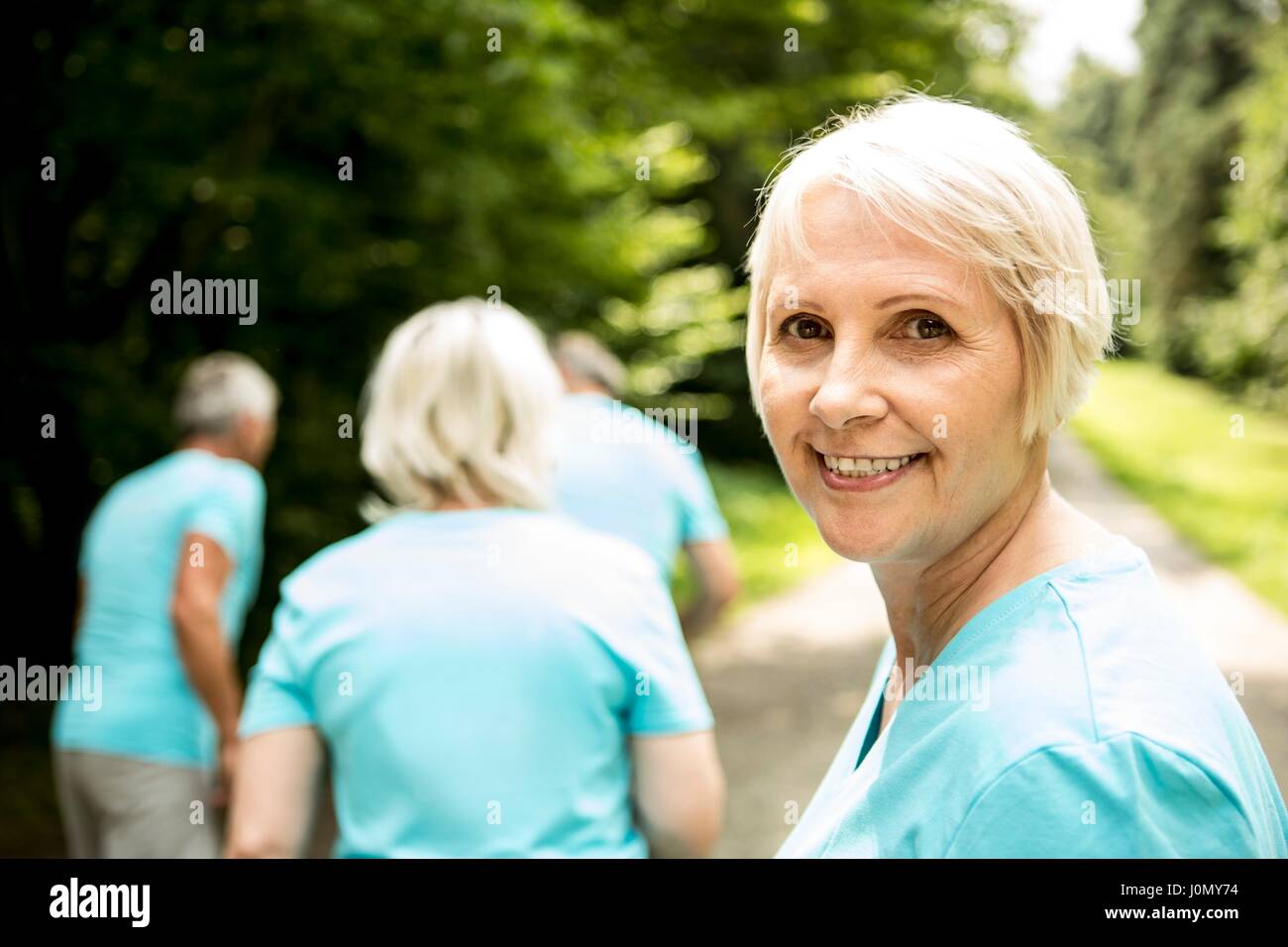 Reife Frau lächelnd mit Freunden im Hintergrund. Stockfoto