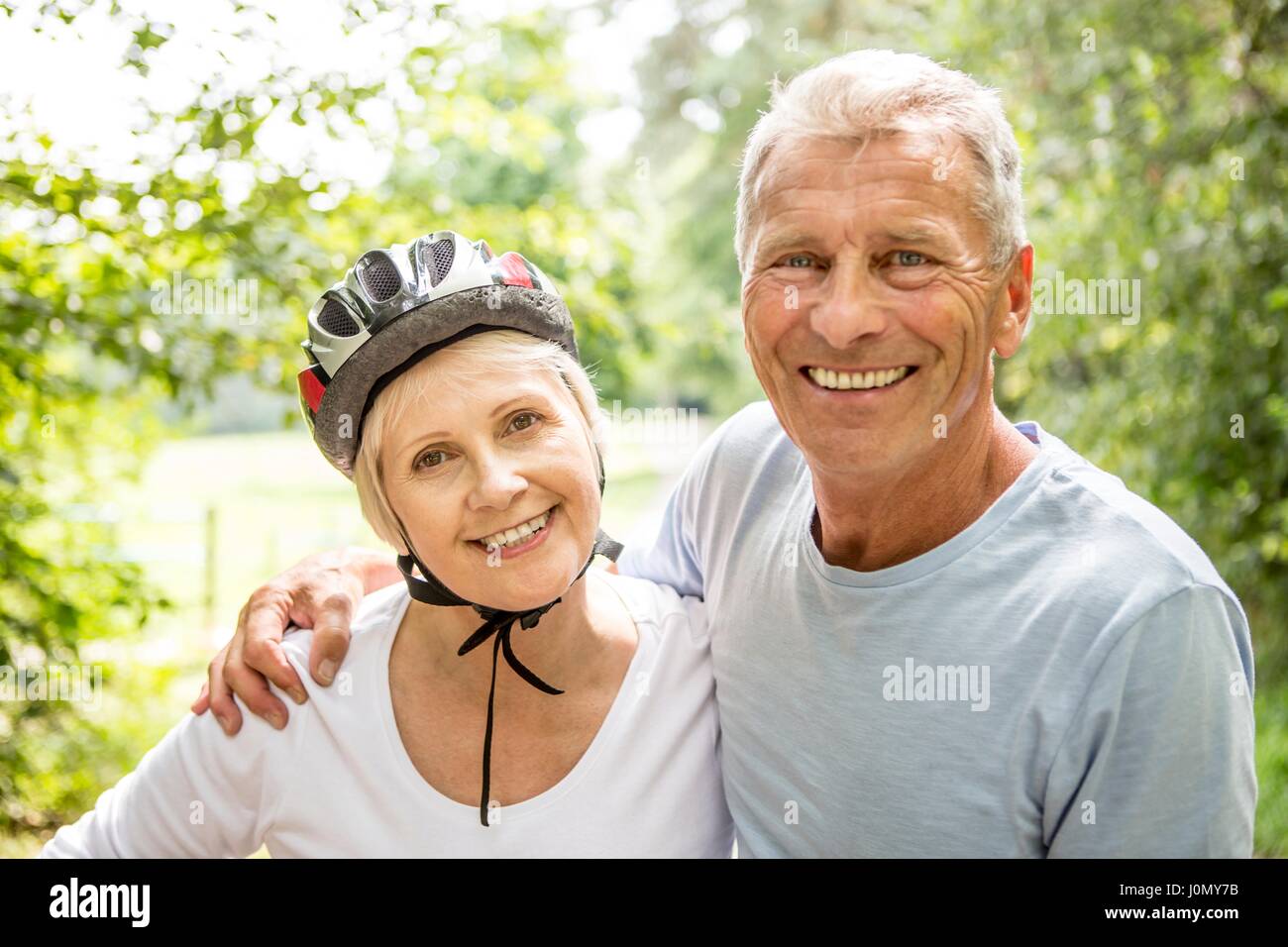 Reife Frau tragen Fahrradhelm, älterer Mann mit Arm um sie. Stockfoto