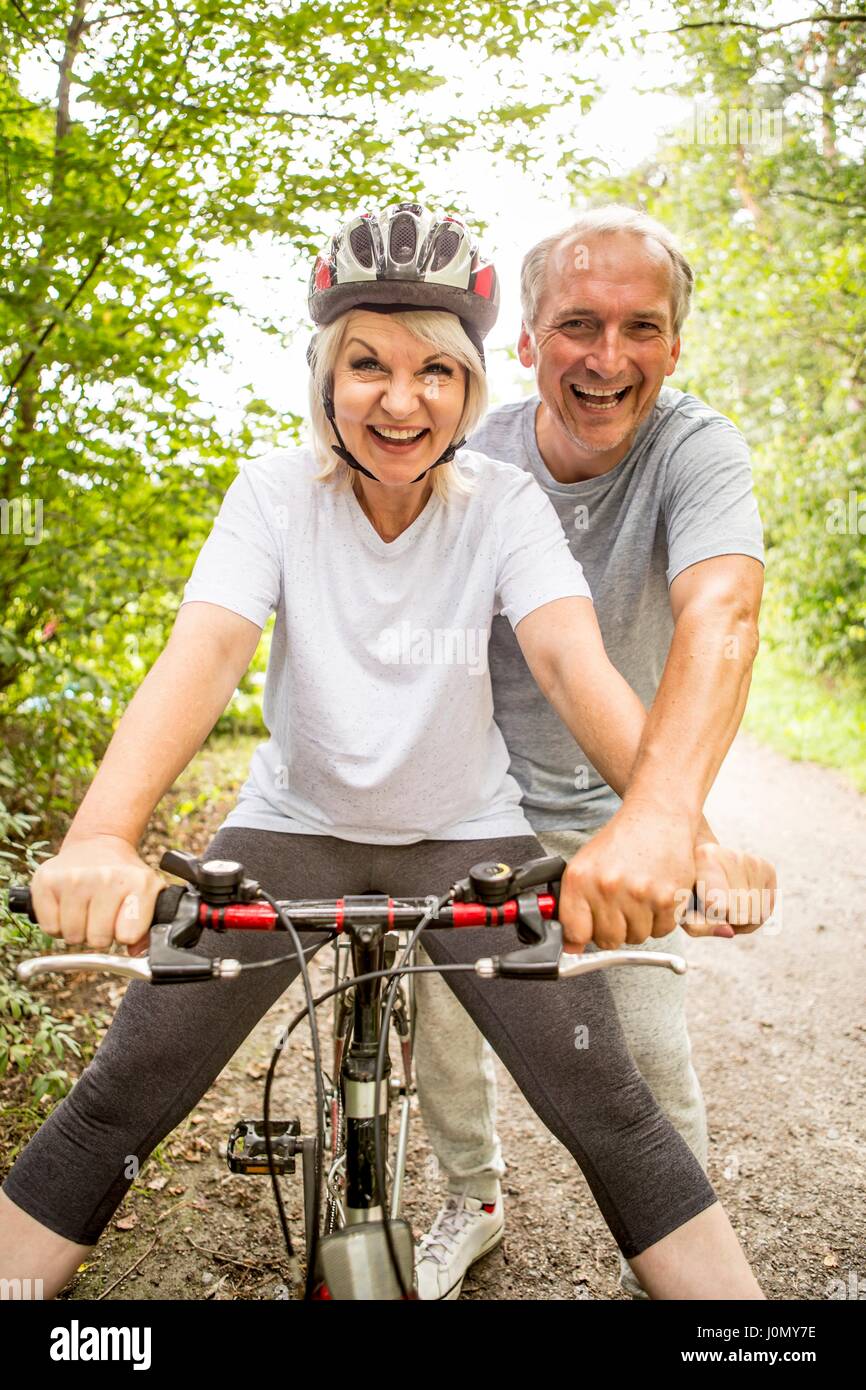 Ältere Frau auf dem Fahrrad, reifer Mann unterstützen. Stockfoto