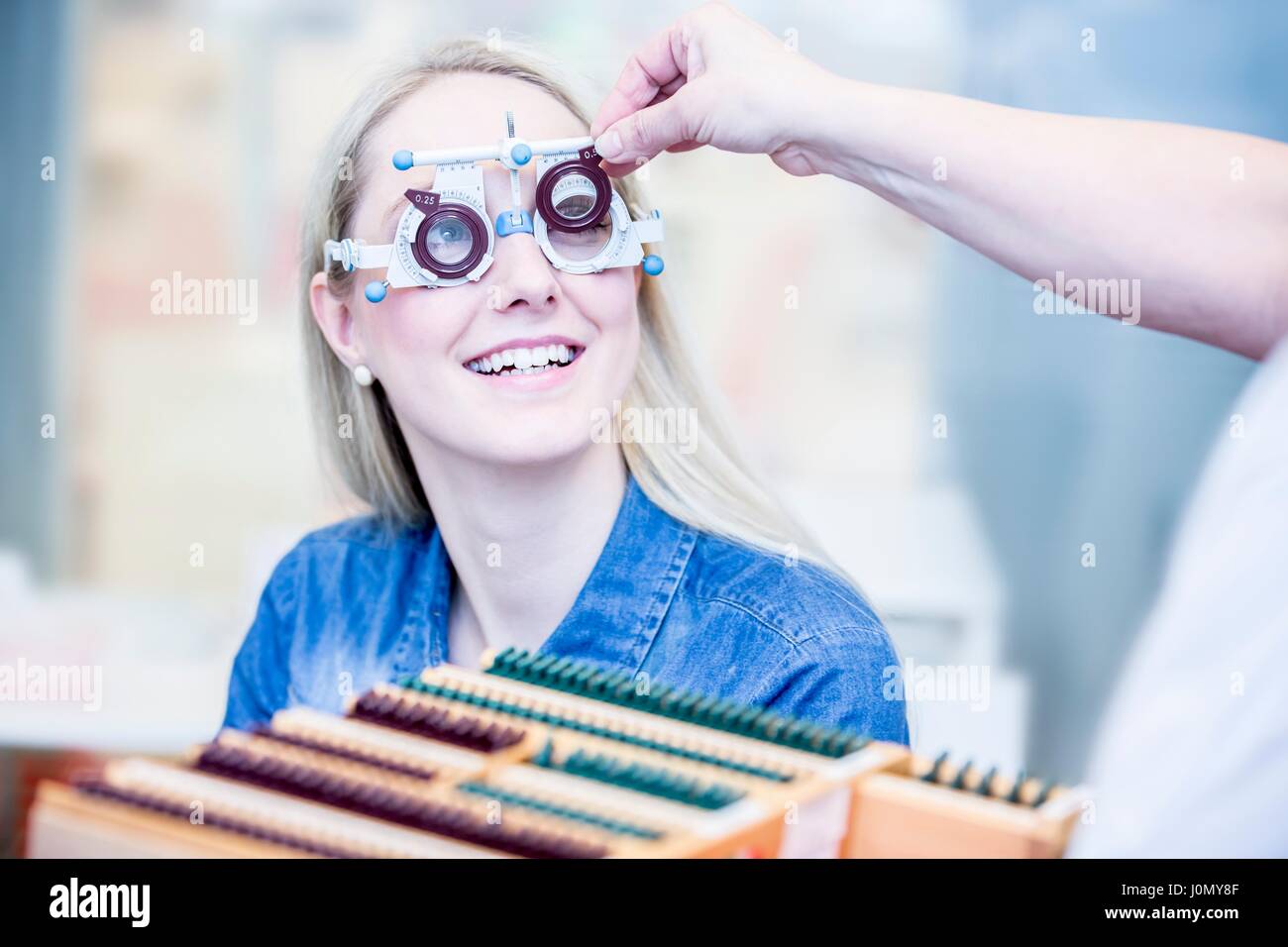 Fröhliche junge Frau mit Augenuntersuchung im Optiker Shop, close-up. Stockfoto
