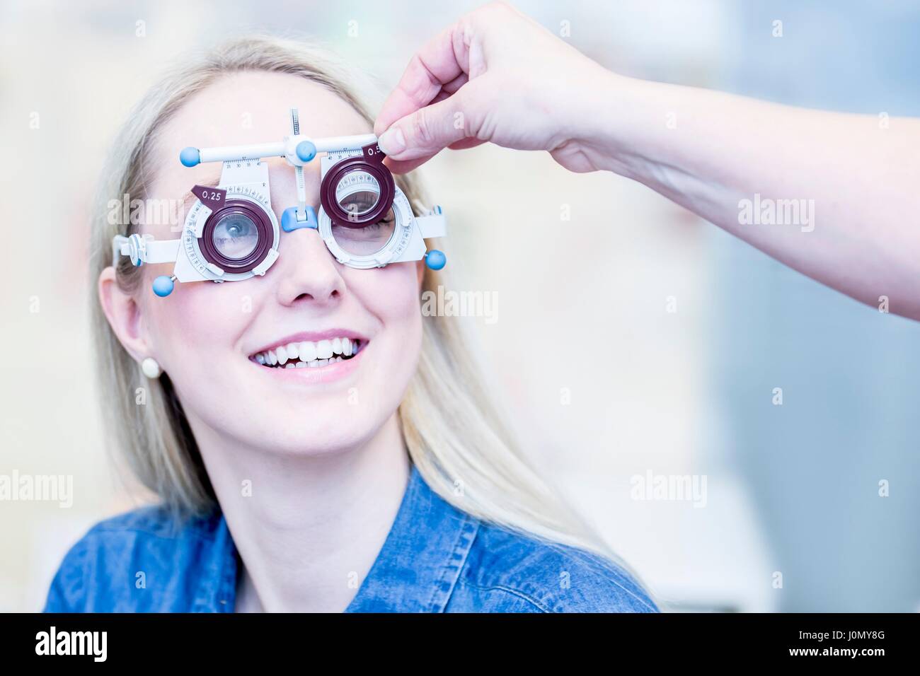 Fröhliche junge Frau mit Augenuntersuchung im Optiker Shop, close-up. Stockfoto