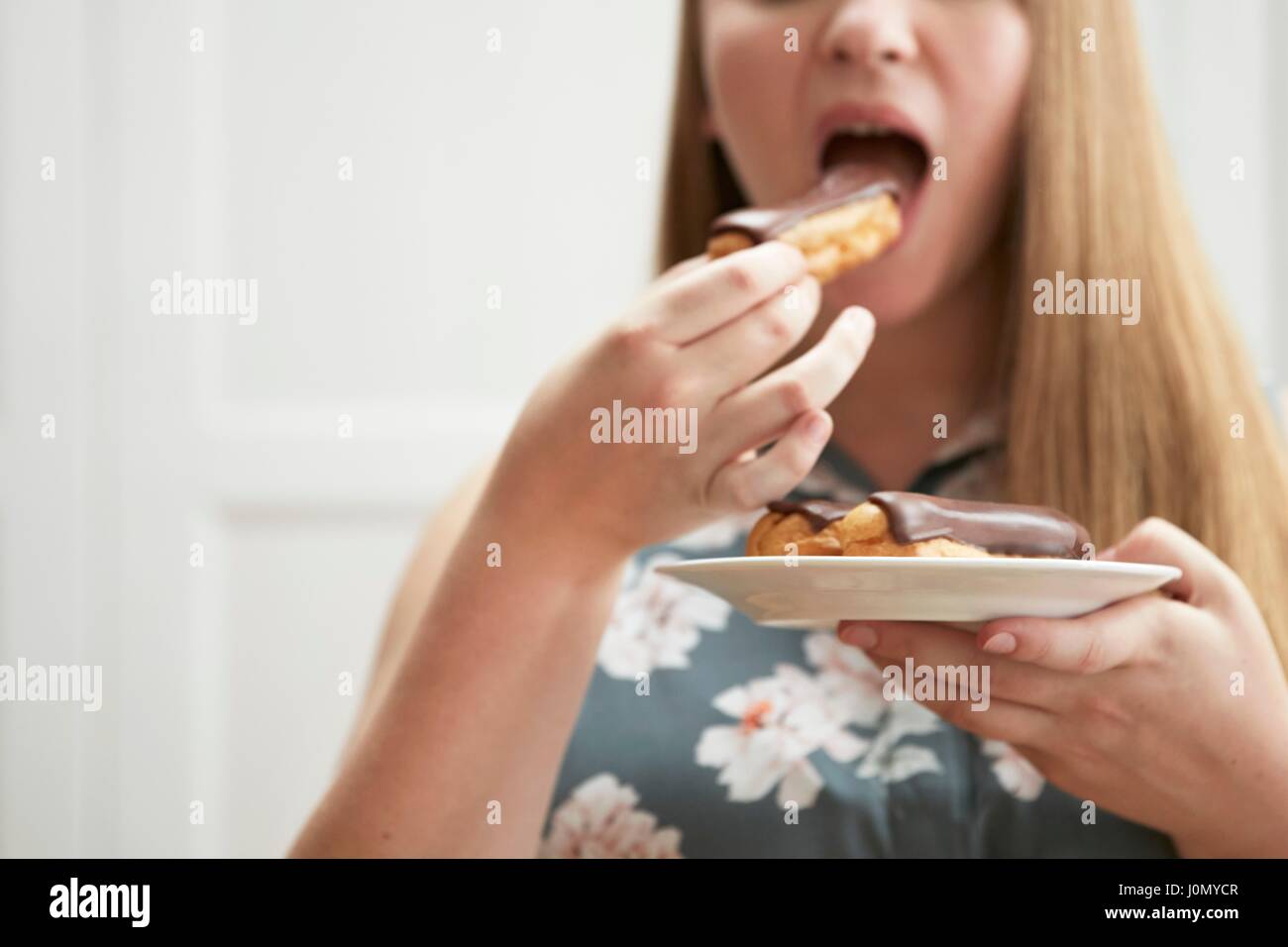 Junge Frau essen Schokolade Eclair. Stockfoto