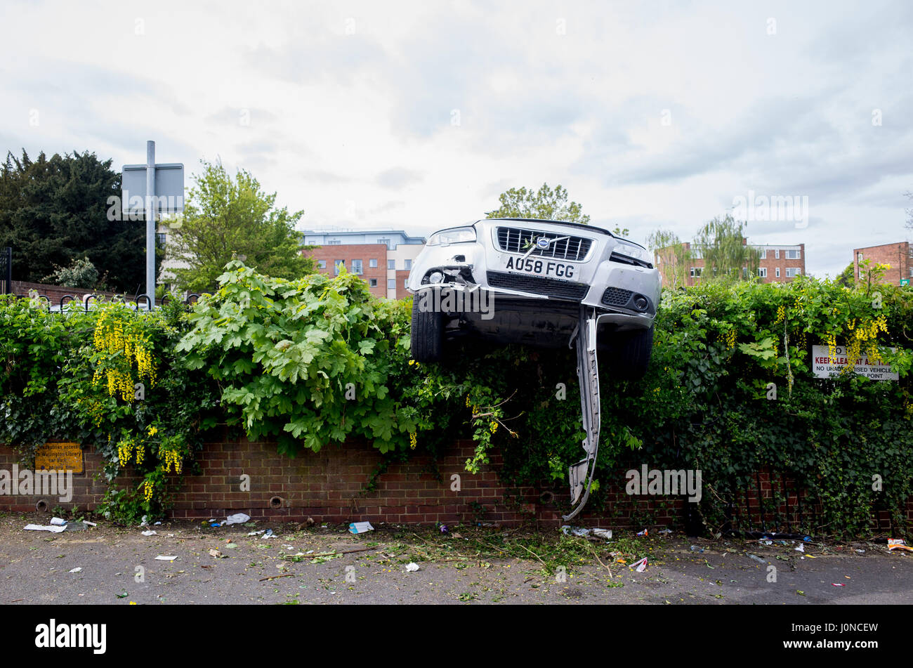 Wallington, Surrey, UK. 15. April 2017. Ein Auto ist durch eine Hecke in Shotfied Parkplatz in Wallington, Surrey abgestürzt. Die front-End hängt Procariously über eine Zufahrtsstraße auf der Rückseite des Shops.  Es ist unklar, ob das Auto die Kontrolle verloren oder absichtlich stürzte wurde, wurde gestohlen zu haben.  Polizei waren anwesend.  Samstag, 15. April 2017. Wallington, London Borough of Sutton. Bildnachweis: Darren Lehane/Alamy Live-Nachrichten Stockfoto