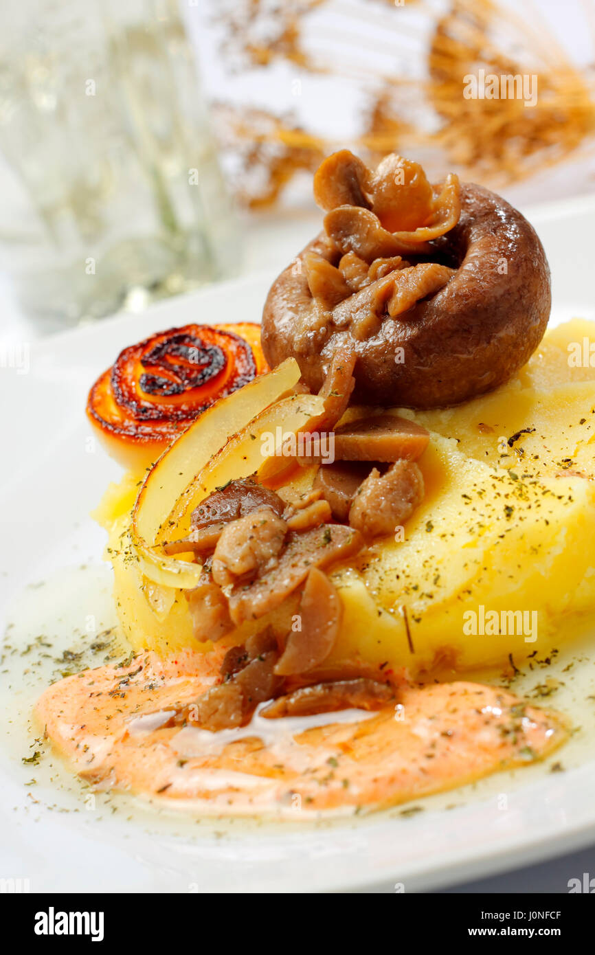 Gebratene Champignons mit Zwiebeln, Kartoffelpüree und Sauce auf Teller mit unscharfen Hintergrund Stockfoto