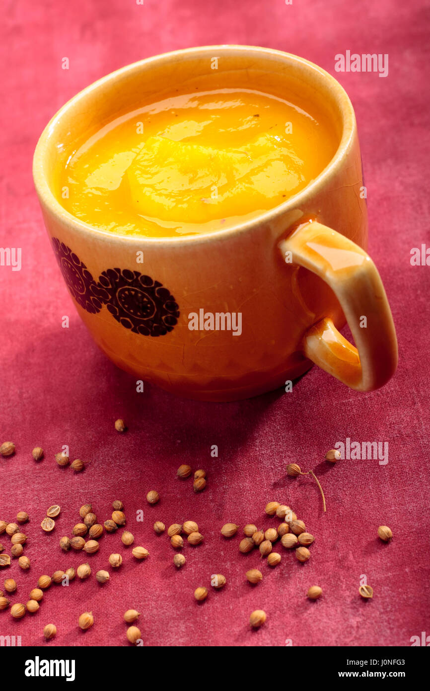 Tasse Kürbis Cremesuppe auf textilen Hintergrund mit Koriandersamen Stockfoto