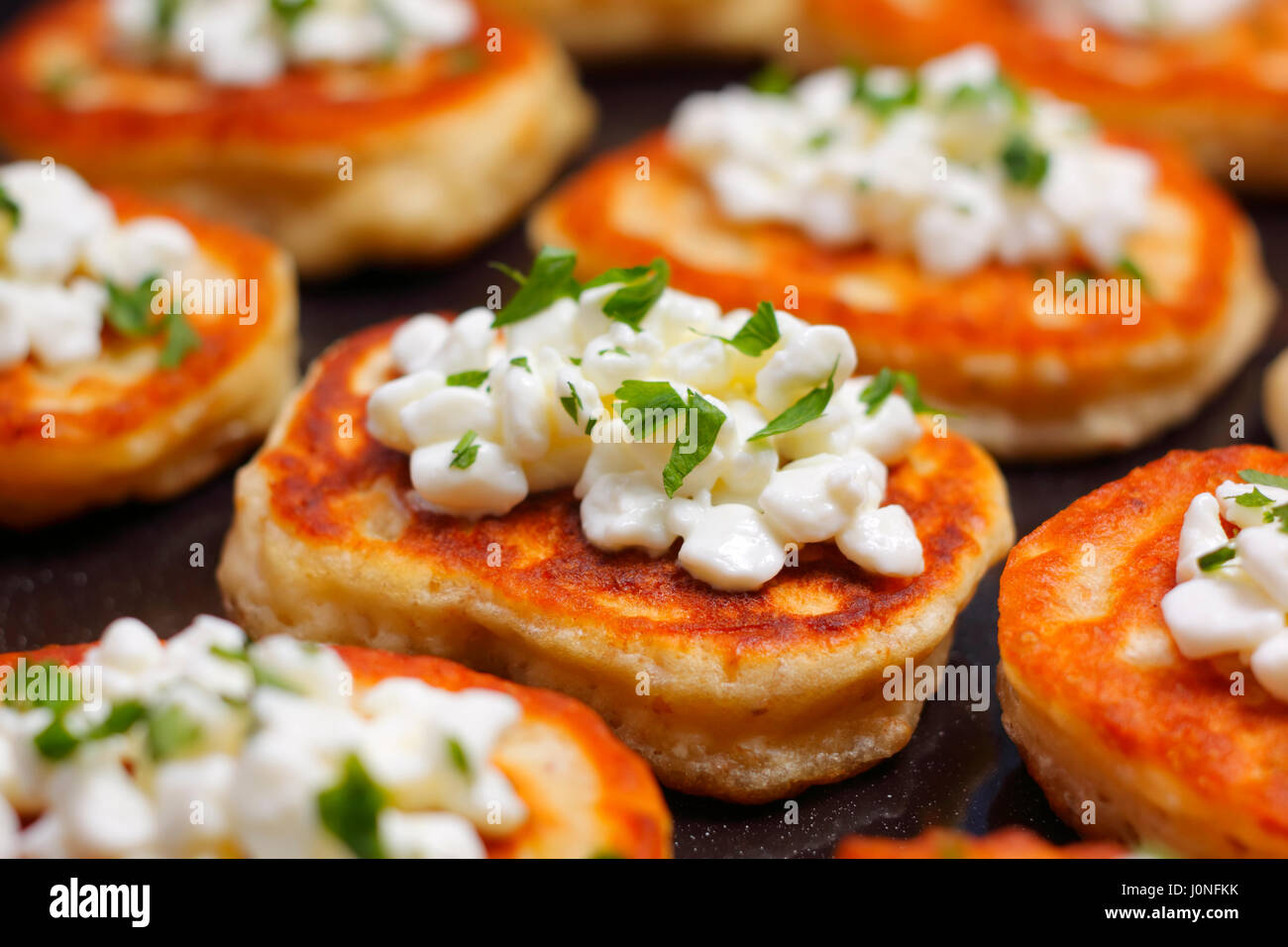 Close-up Blinis (aus Weißmehl) mit Hüttenkäse und gehackter Petersilie Stockfoto