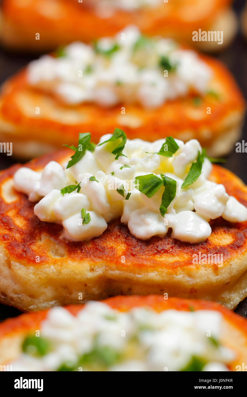 Nahaufnahme von Blinis (aus Weißmehl) mit Hüttenkäse und gehackter Petersilie Stockfoto