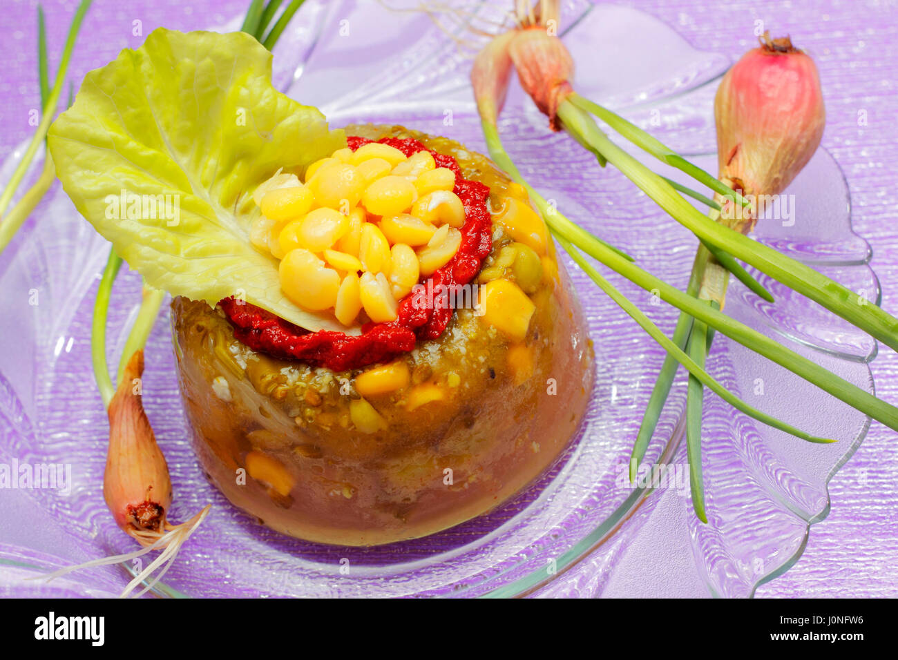 Gemüse-Gelee mit Tomatensauce, Mais und Salat auf Glasplatte Stockfoto