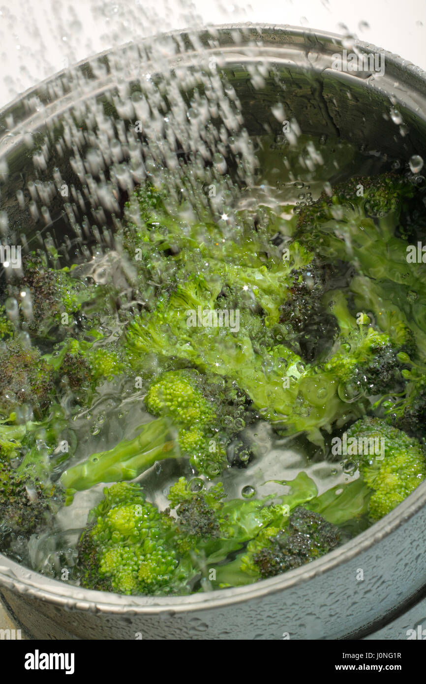 Gießen frisches Wasser in Topf mit Brokkoli Stockfoto
