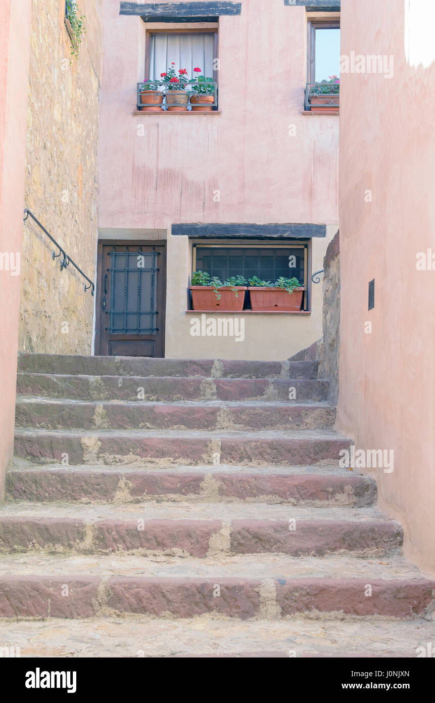 Stadt von Albarracin, verstanden als spanisches Nationaldenkmal in Teruel (Spanien). Treppen auf Gasse gegenüber typischen rötlichen Häuser. Sommer. Ländlicher Urlaub Stockfoto