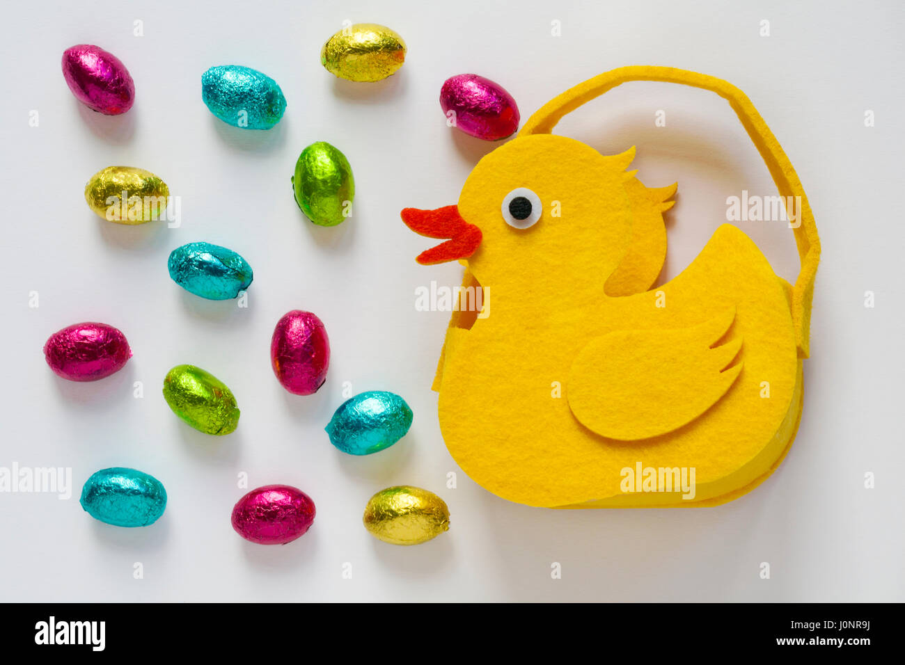 Filz Küken mit Ostereiern - choccy Eier solide Milch Schokolade Eier - auf weißem Hintergrund - bereit für Ostern Stockfoto