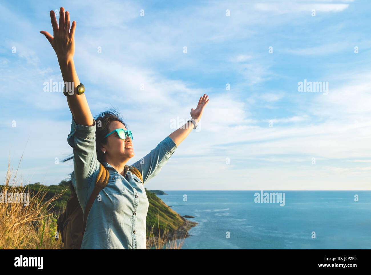 Glückliche junge Reisende Frau hob Arm bis zum Himmel genießen Sie eine schöne Natur an Spitze des Berges und Blick aufs Meer, Freiheit Fernweh Backpacker Konzept. Stockfoto