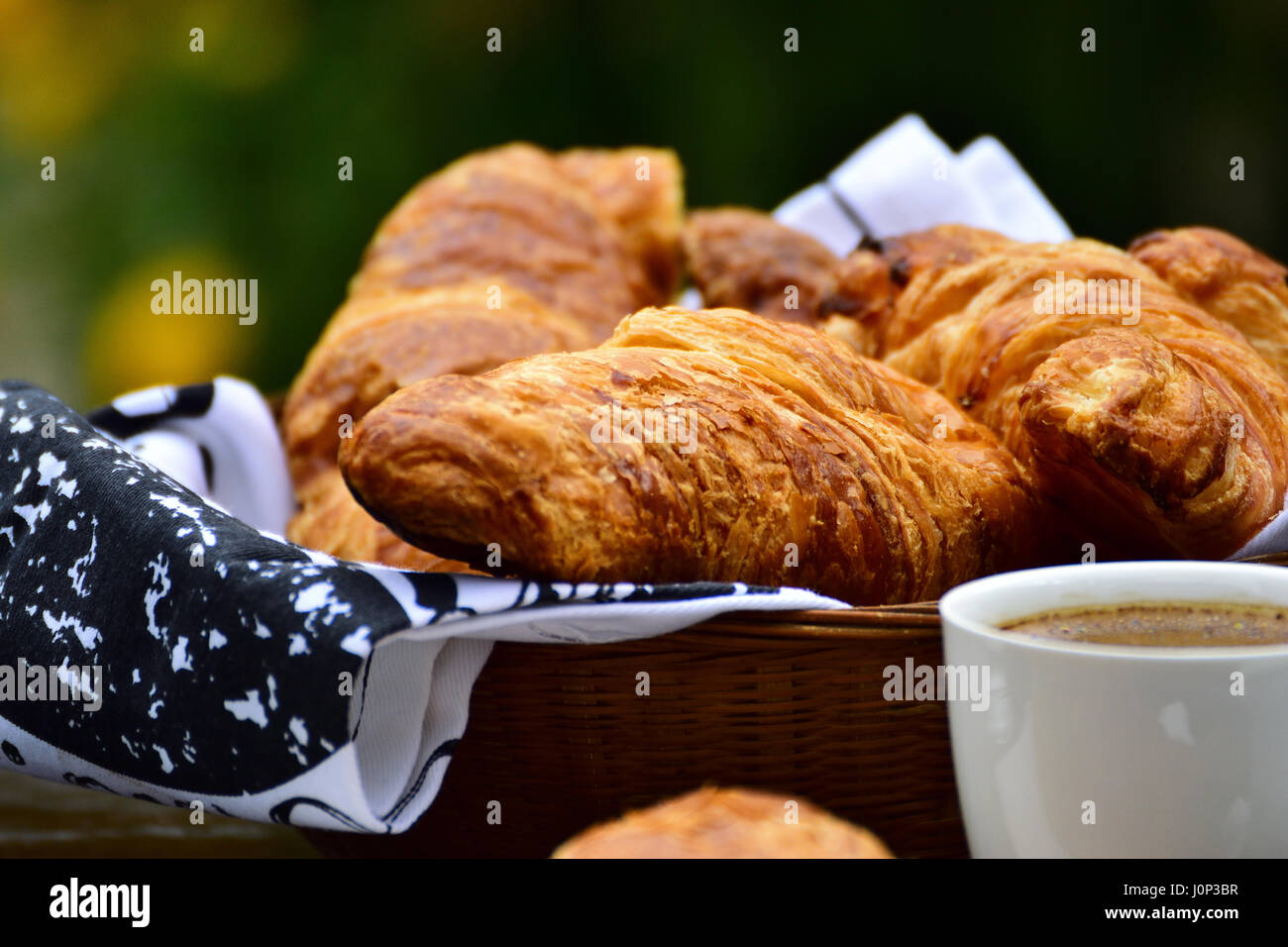Korb mit frischem französischen Croissants, eine Tasse Kaffee, Ansicht schließen, Bokeh Stockfoto