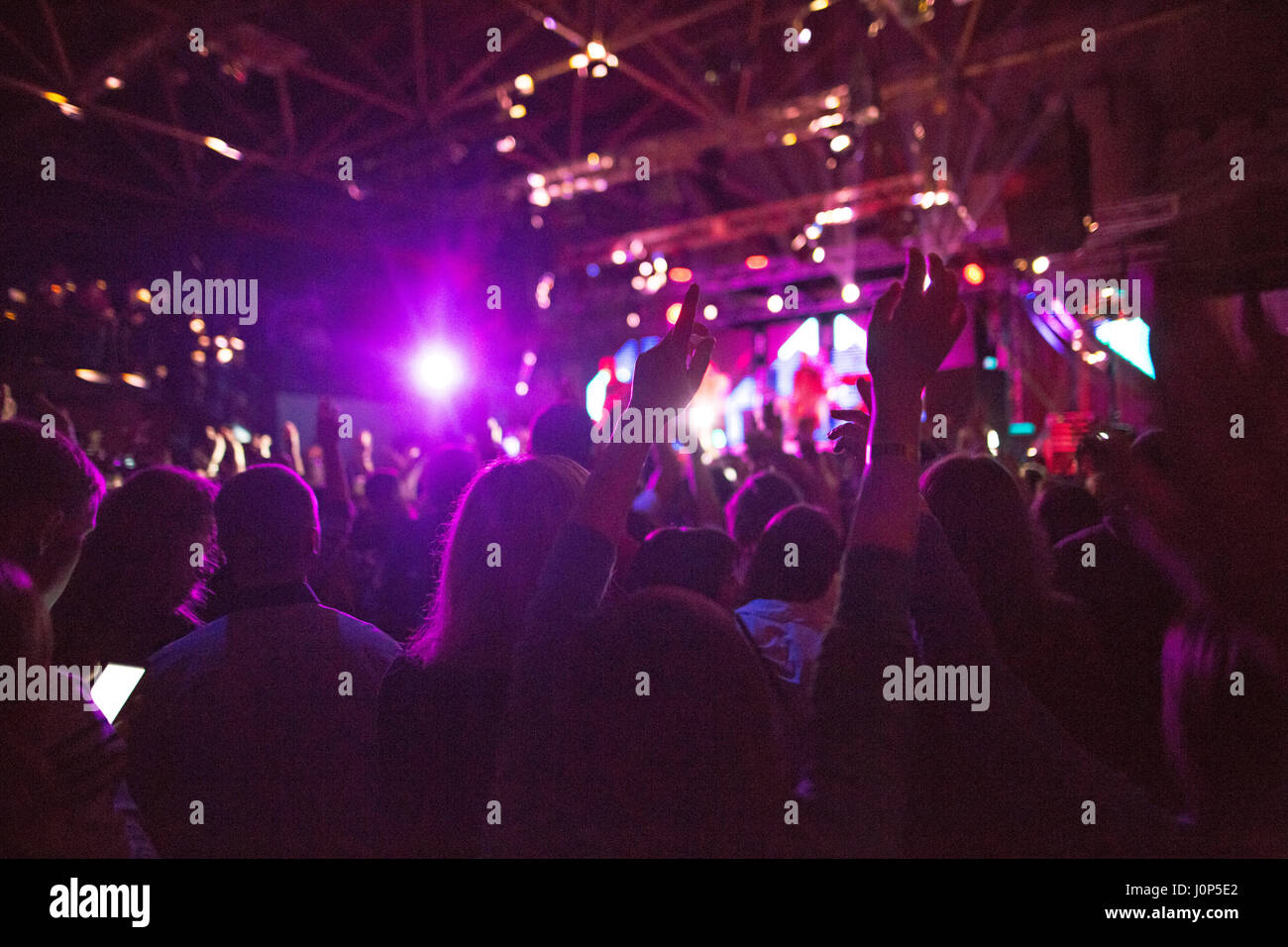 Die Silhouetten der Konzert drängen sich vor hellen Beleuchtung Stockfoto