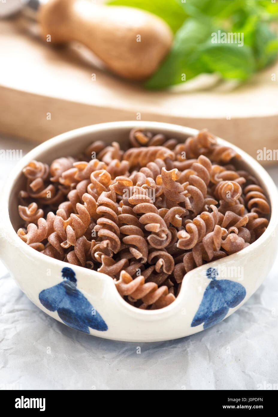 Teigwaren aus brauner Reis glutenfrei, roh in eine kleine Schüssel in Fenster Licht mit einem Fokus-Hintergrund, Text hinzufügen oder kopieren Raum gedreht Stockfoto