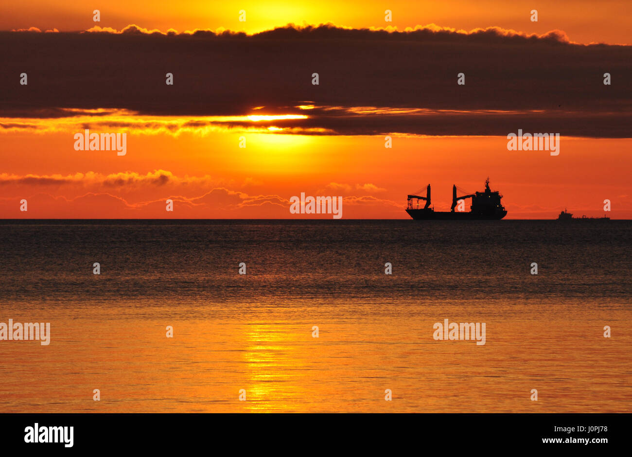 Hellen goldenen Sonnenaufgang über der Ostsee in Polen mit einem Schiff am Horizont Stockfoto