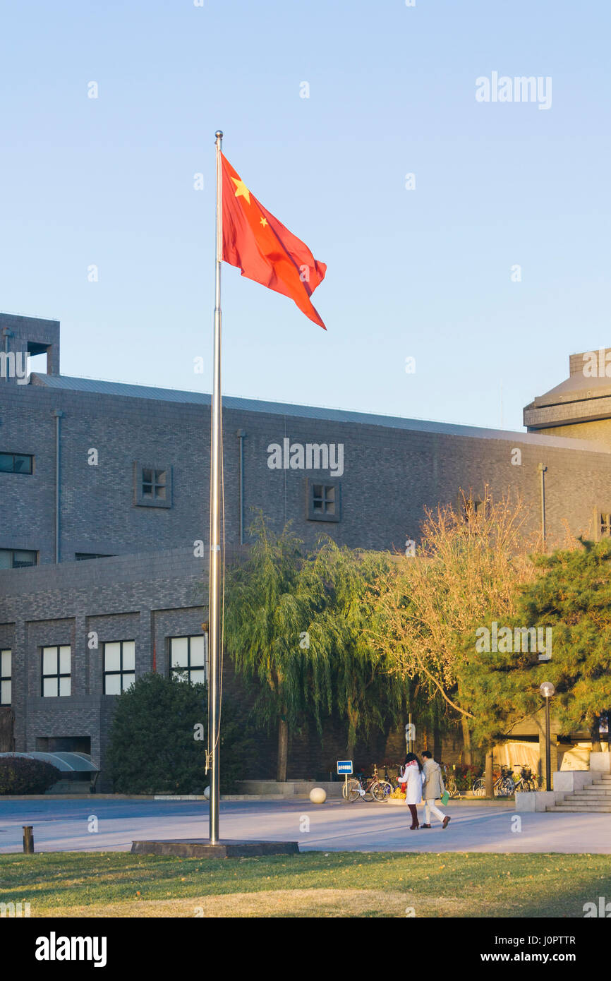 16. November 2014, Peking, China. Eine chinesische Flagge in die Kommunalfinanzen namens The Central Academy of Fine Arts (CAFA), mit zwei Personen zu Fuß unter der Flagge Stockfoto