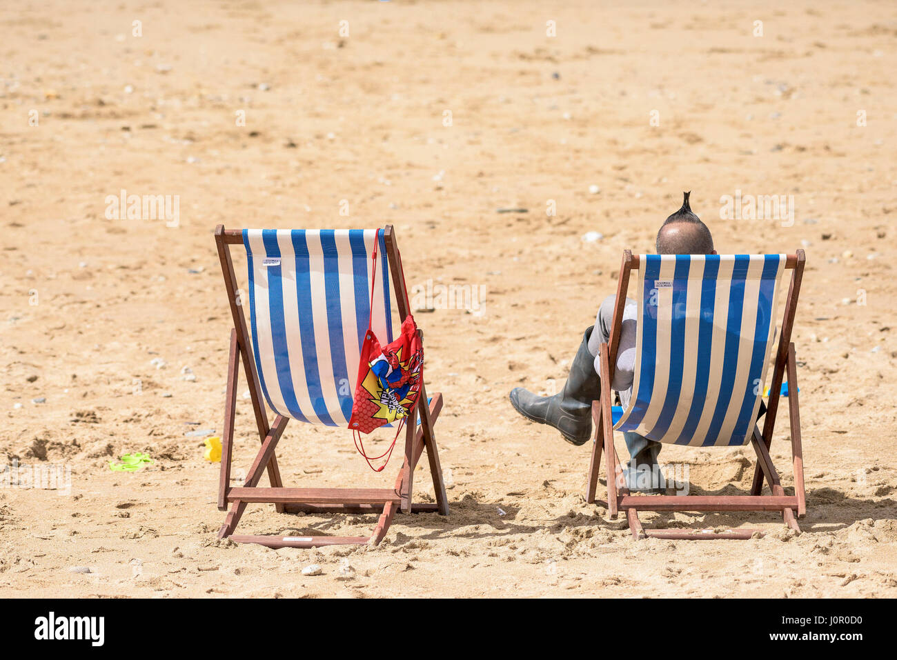 Fistral Beach Newquay Liegestühle Man Mohican Frisur Entspannende Entspannung Sitzen Strandtourismus Strandurlaub Urlaub Freizeit Cornwall Stockfoto