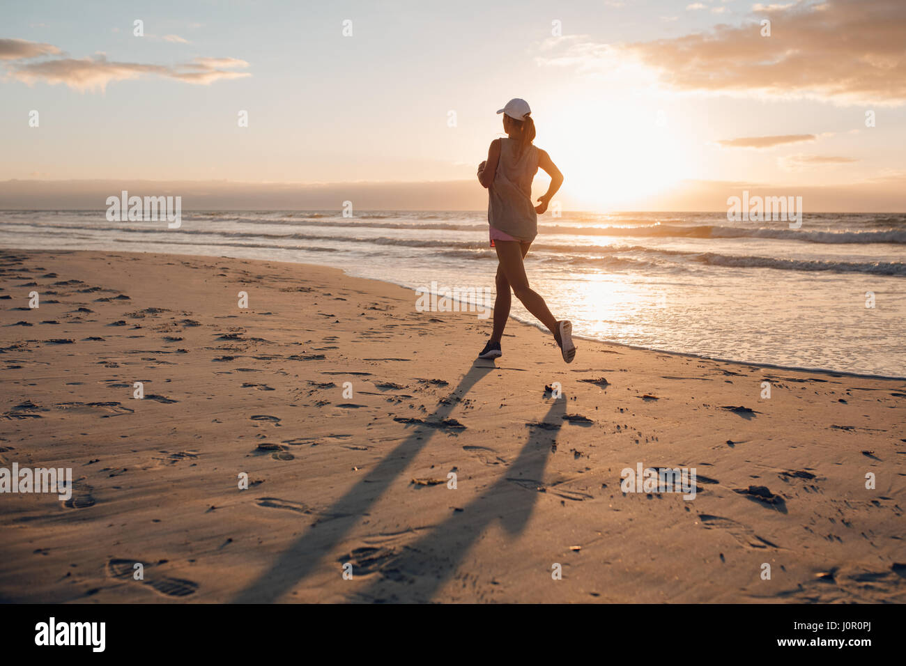 Rückansicht Schuss der jungen Frau, die morgens am Strand laufen. Gesunde Frauen Joggen am Ufer Meeres. Stockfoto