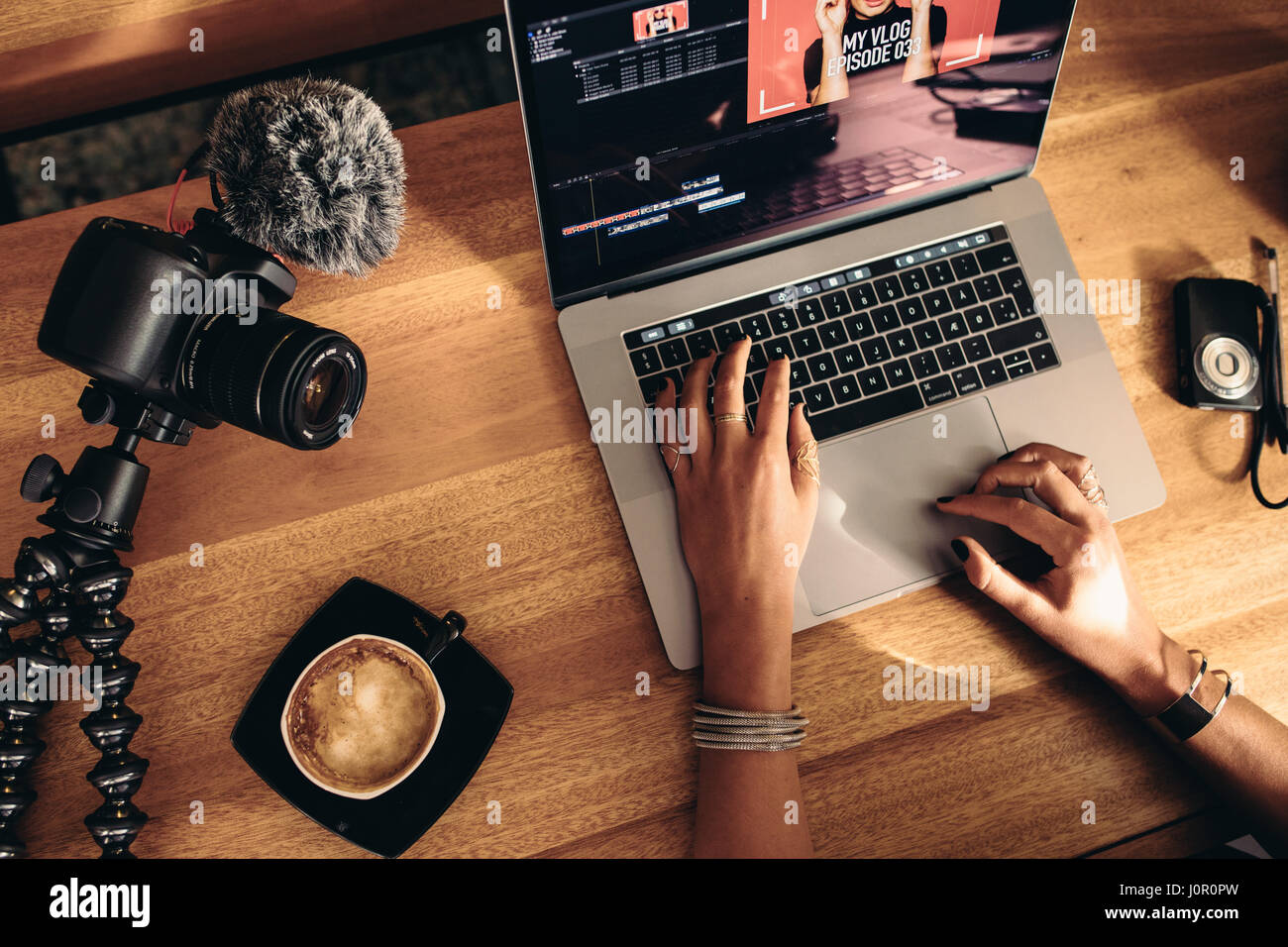 Draufsicht der weiblichen Vloggerin Videobearbeitung auf Laptop. Junge Frau auf Computer mit Kaffee und Kameras auf Tisch arbeiten. Stockfoto