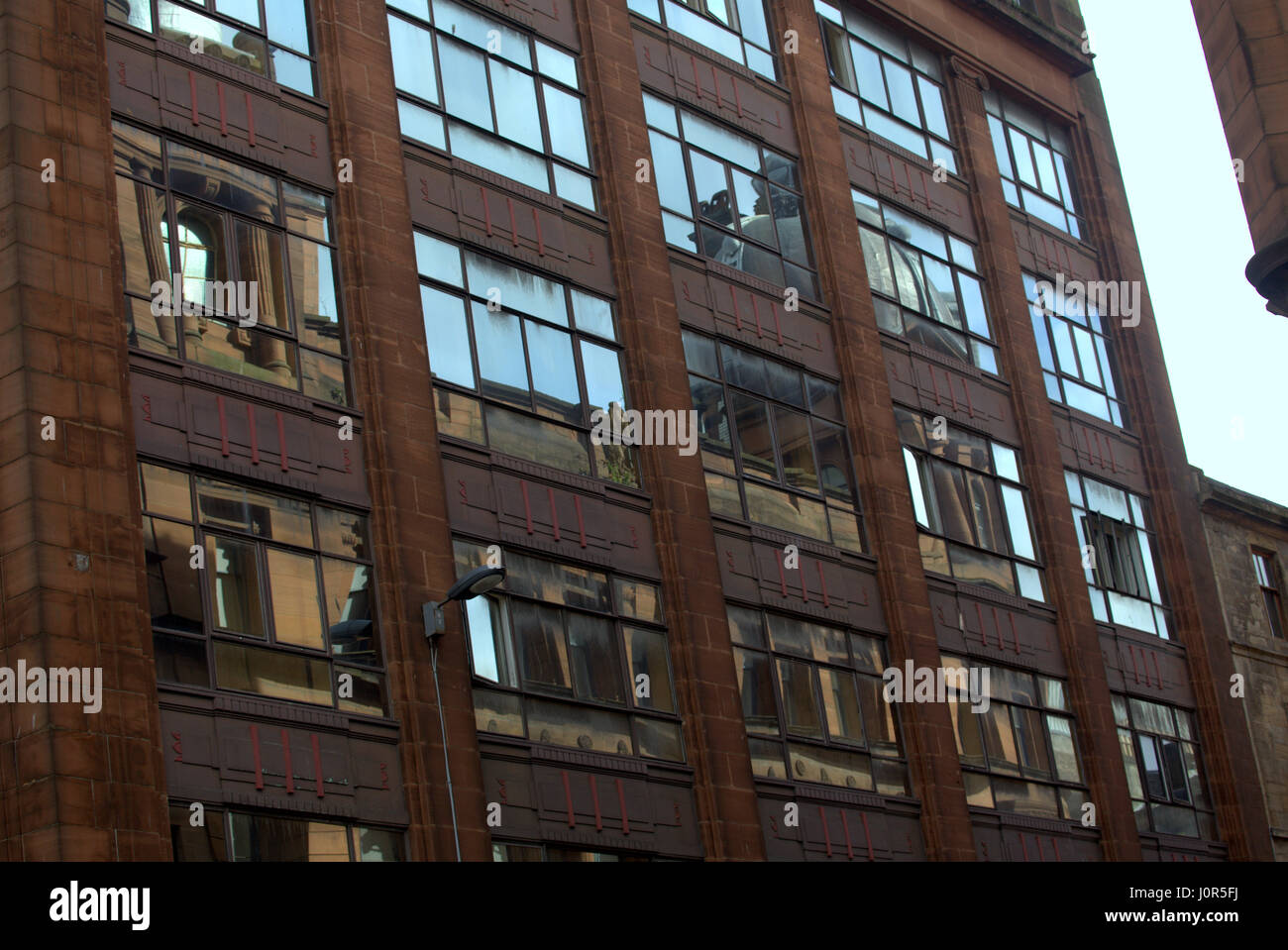 Reflexion von Glasgow viktorianischen roten Sandstein verzierten Gebäude im späteren 20. Jahrhundert Art Deco industrielle Fassade Stockfoto
