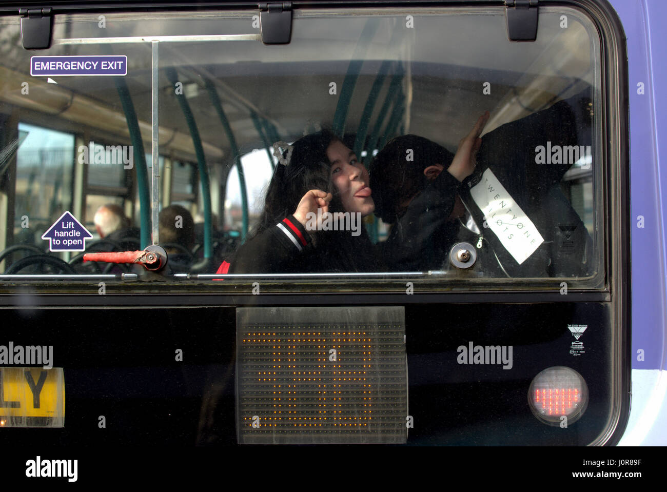 Kinder über grimassen an der Rückseite eines Busses messing Tupfen Stockfoto