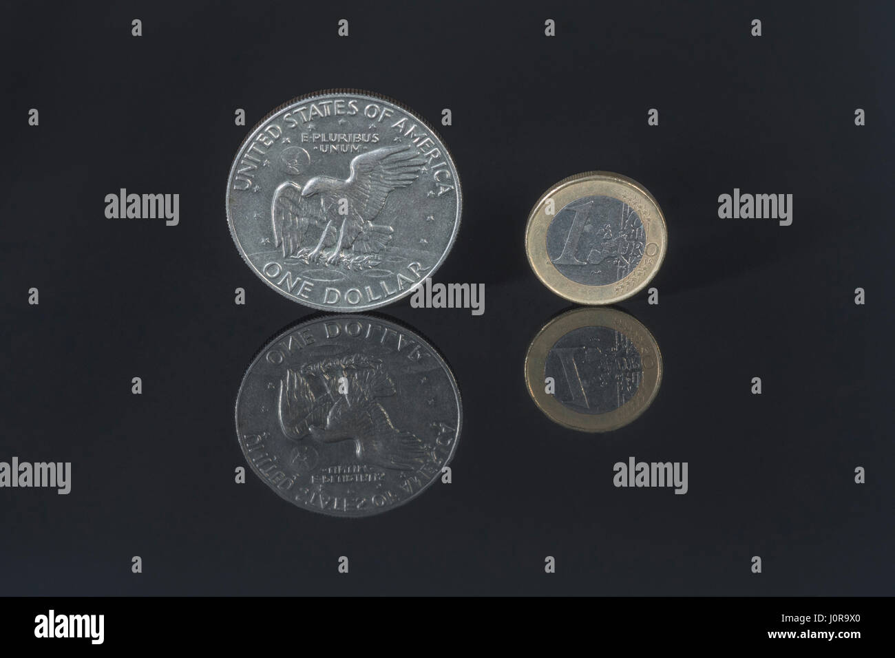 US $ 1 Dollar & 1 Euro Münze auf dunklem Hintergrund - Metapher für US-Dollar-Euro-Wechselkurs, Zahlungsbilanz und Handel. Stockfoto