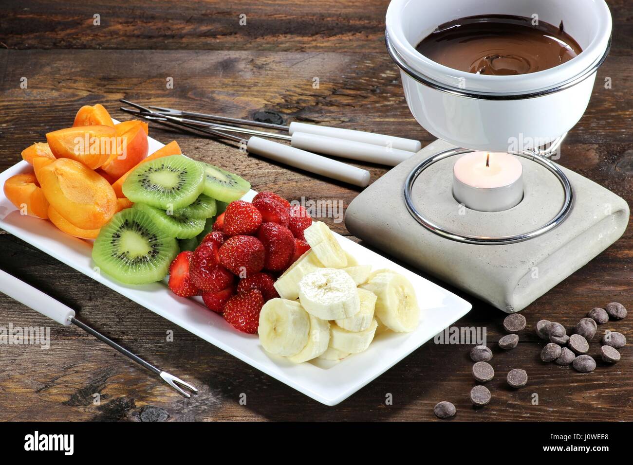 Schokoladenfondue mit Obst Sortiment auf hölzernen Hintergrund Stockfoto