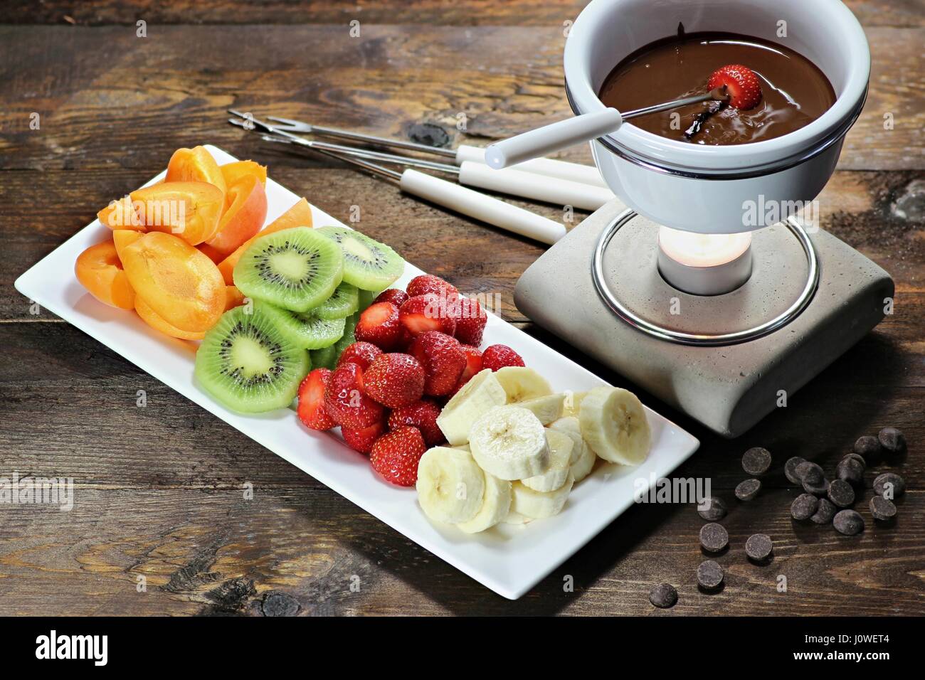 Schokoladenfondue mit Obst Sortiment auf hölzernen Hintergrund Stockfoto