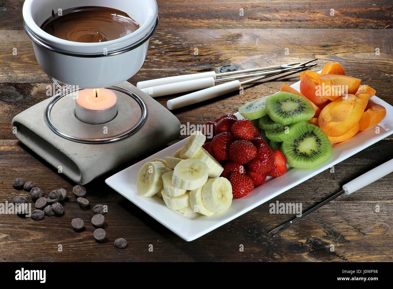 Schokoladenfondue mit Obst Sortiment auf hölzernen Hintergrund Stockfoto