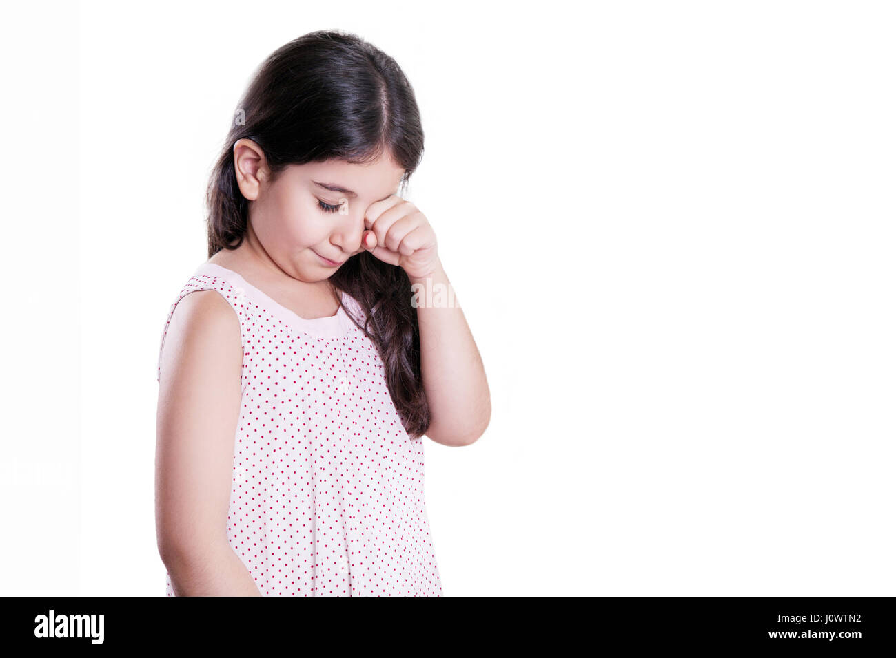 Traurig weinende unglücklich kleine schöne Mädchen mit dunklen Haaren und Augen. Studioaufnahme, isoliert auf weißem Hintergrund. Stockfoto